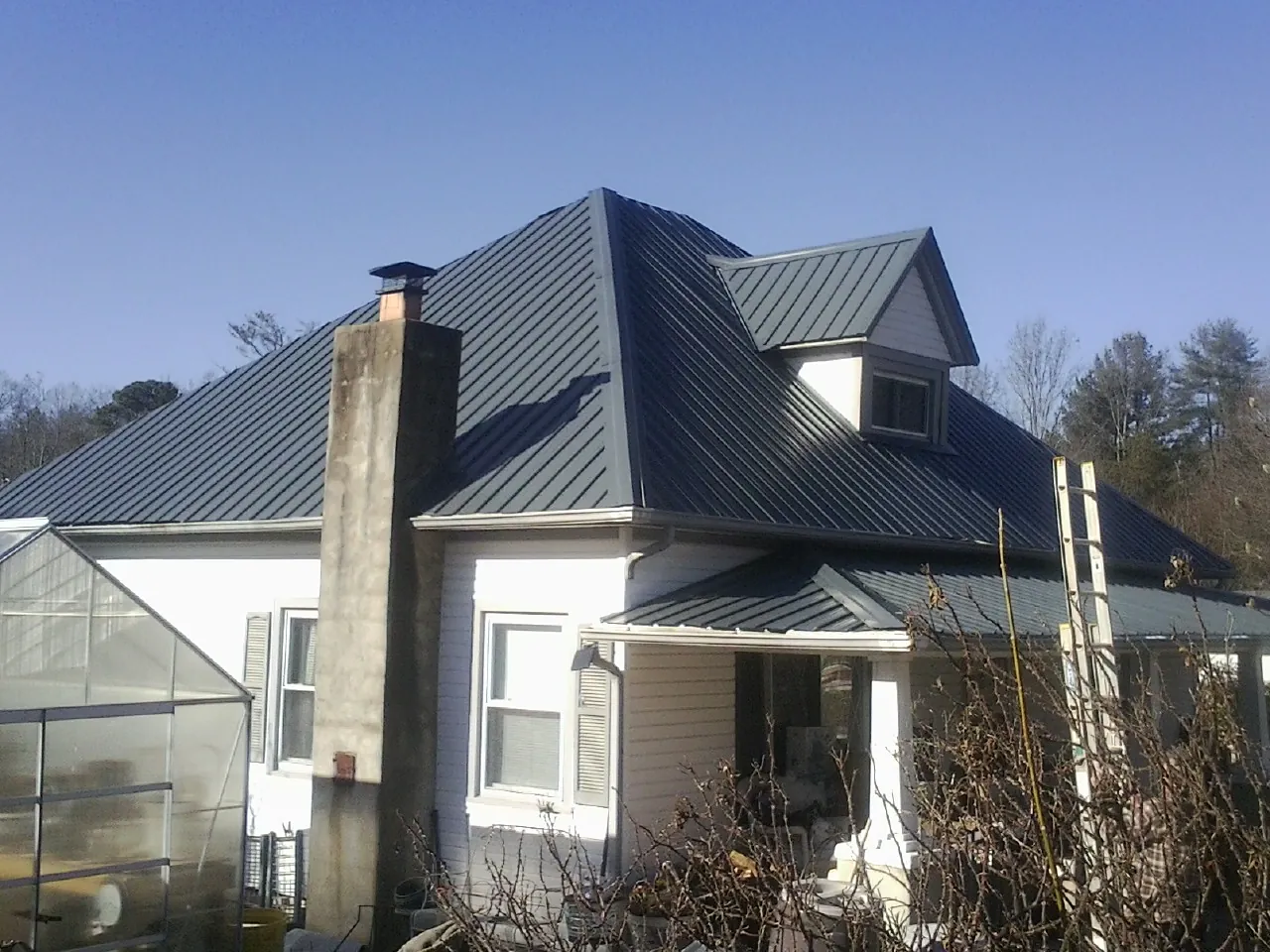 Dark blue standing seam metal roof on a white farmhouse with dormer — Slate & Tile Roof Repair by Roofing Brothers in Hockingport