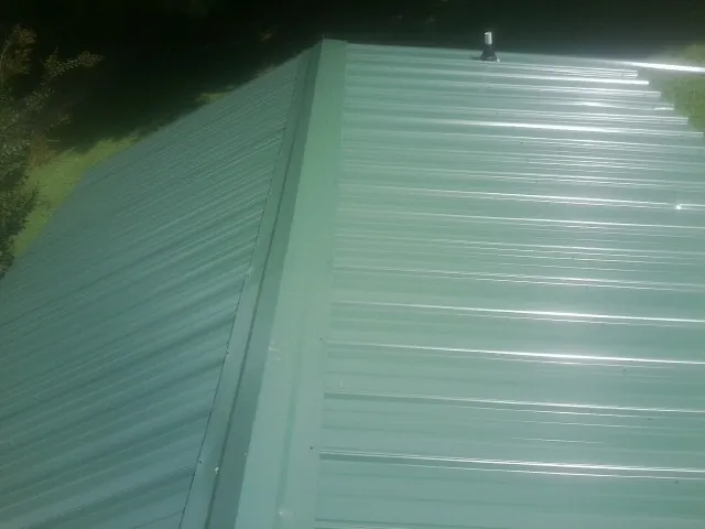 New green metal panels meeting at the ridge of a roof — Flat Roof Repair work by our crew in Hockingport