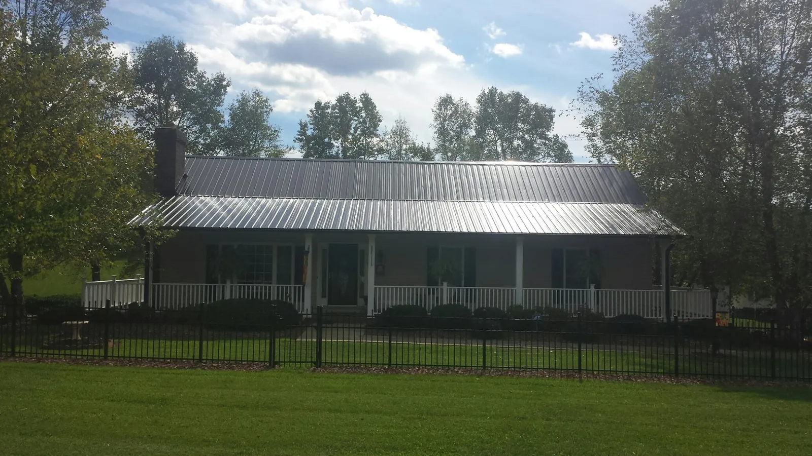 Gray metal roof on a brick ranch with a full width front porch — Gutter Guard Installation work by our crew in Hockingport