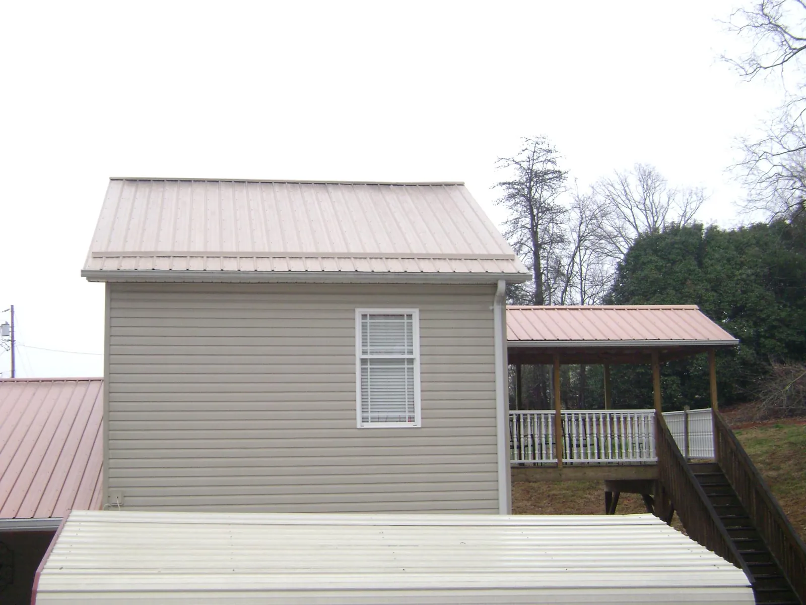 Tan metal roofs on a two story addition and attached porch, from a Roof Replacement job in Hockingport