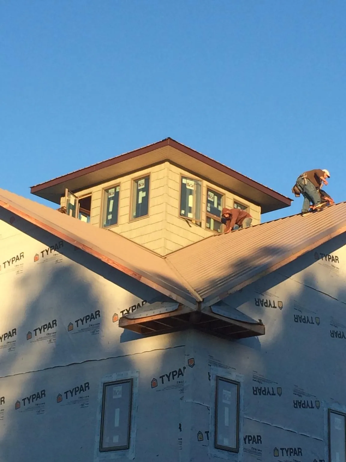 Roofers working around a rooftop cupola on a new metal roof at sunset — Roof Waterproofing in Hockingport by Roofing Brothers
